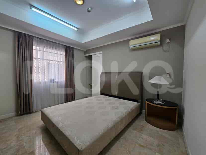 A well-lit bedroom with a large bed and side table.