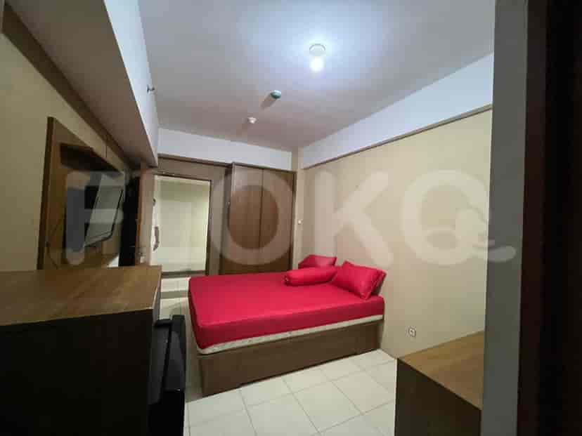 A compact bedroom with a red bed, wooden wardrobe, and a wall-mounted TV.