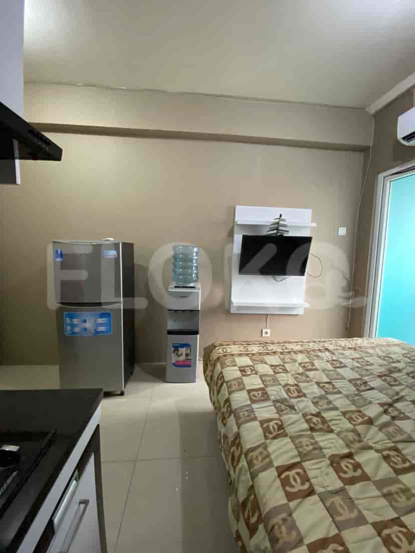 A small apartment bedroom with a bed and a kitchenette.