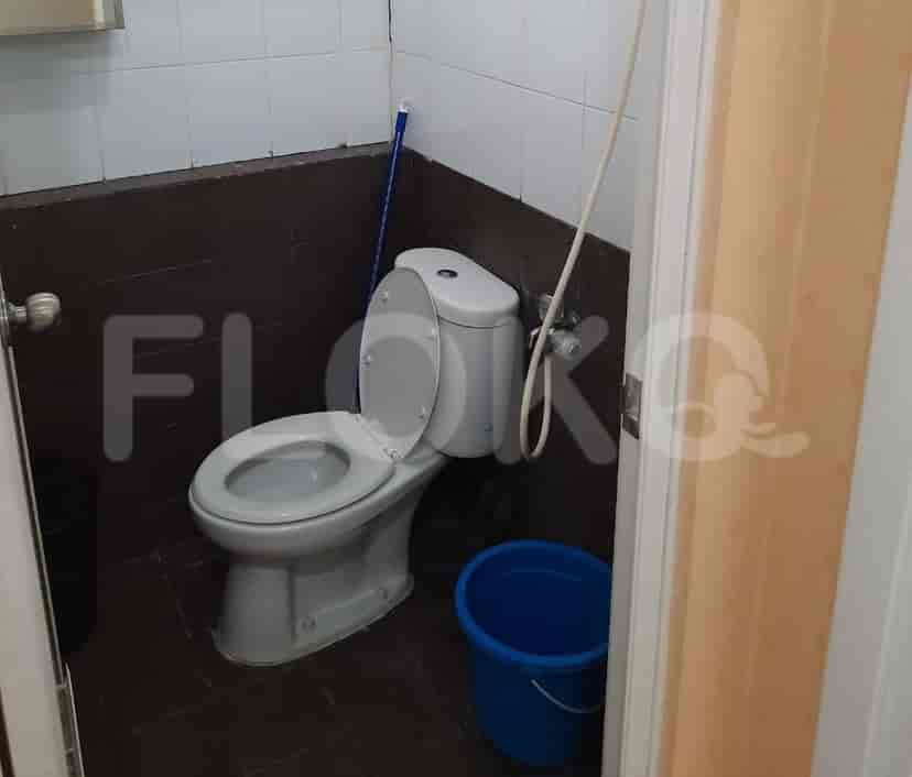 A bathroom with a toilet and a bucket.
