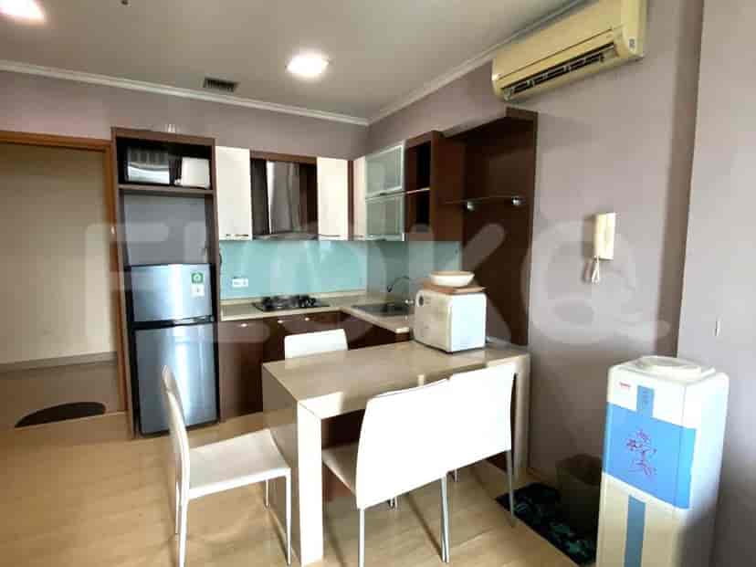 Dapur ringkas dengan meja makan, peralatan, dan dispenser air.