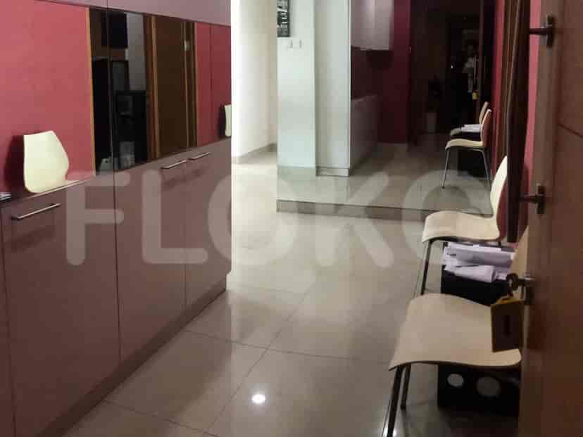 Lorong dengan lemari, kursi, dan cermin, mengarah ke ruangan lain.