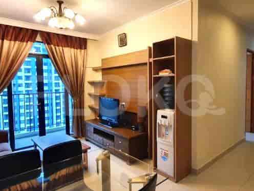 Ruang tamu dengan jendela besar, TV, dan penyimpanan built-in.