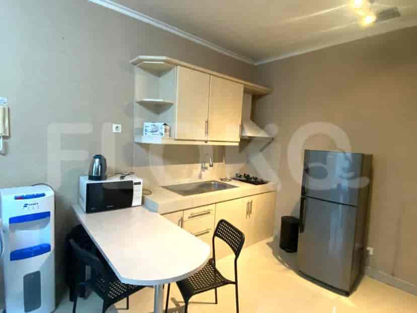 A small kitchen with basic amenities including a microwave, fridge, and dining table.