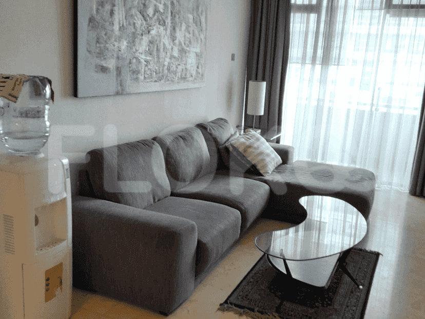 Ruang tamu modern dengan sofa berbentuk sectional, meja kopi, dan dispenser air.
