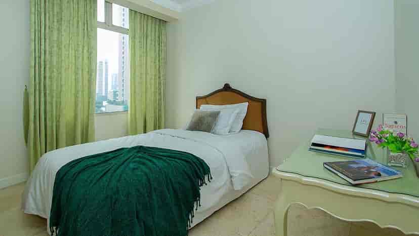 A bedroom with a single bed, desk, and large window.