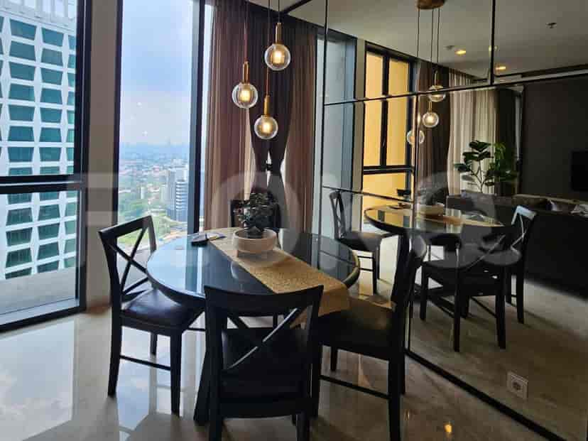 Area makan dengan meja kaca bundar, kursi hitam, dan pemandangan kota.
