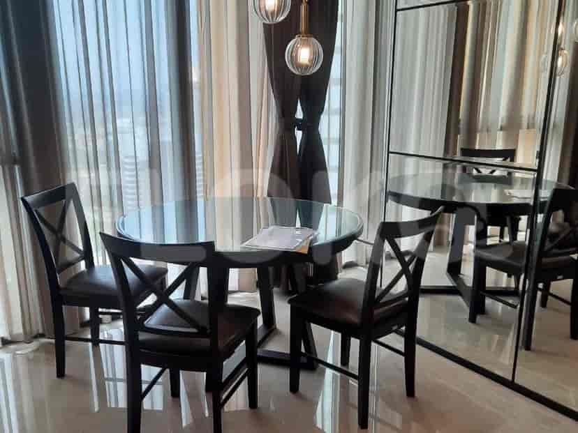 A dining area with a round glass-top table and four dark wooden chairs.