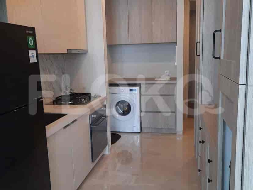 A modern kitchen with wooden cabinets, a black refrigerator, and a washing machine.