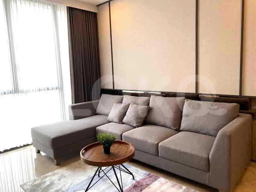 Ruang tamu modern dengan sofa berbentuk L, meja kopi bundar, dan gorden tipis.
