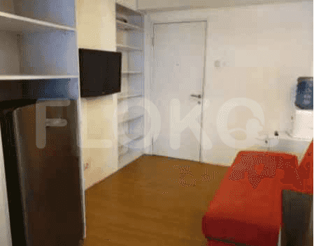 Area tempat tinggal yang menampilkan sofa merah, rak, dan TV.