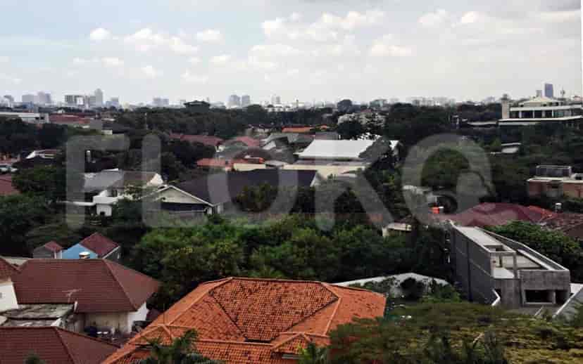 Pemandangan kota dengan gedung tinggi, pepohonan, dan langit cerah.