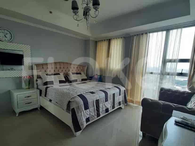 A luxurious bedroom featuring a king-sized bed, chandelier, and large windows.