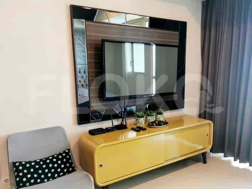 A yellow cabinet under a mounted TV in a living room.