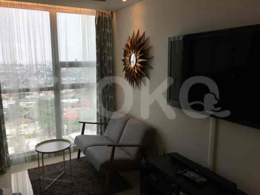 A stylish living room with a sofa, TV, and large windows overlooking the cityscape.