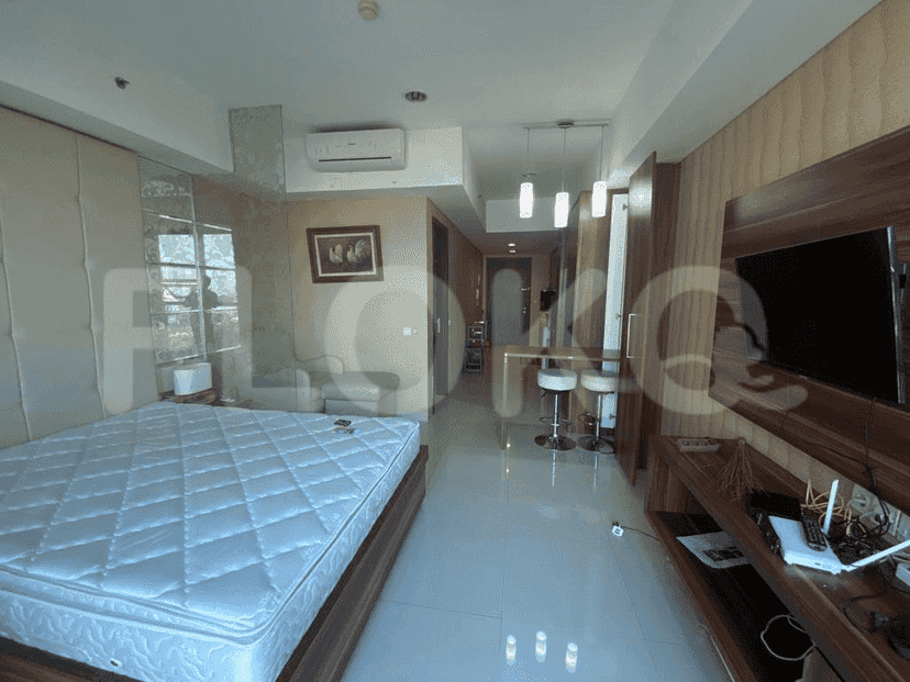 Bedroom area with kitchenette in the background.