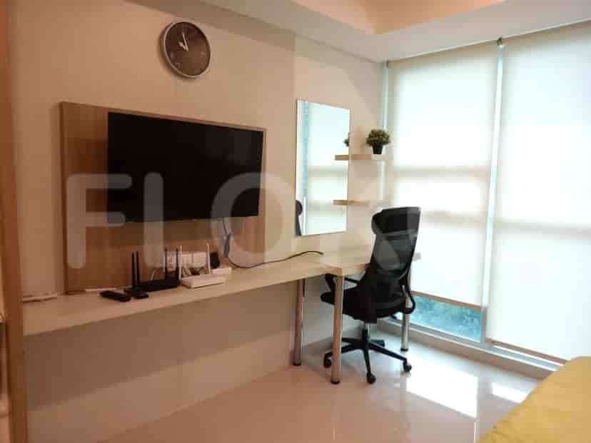 A bedroom with a desk, TV, and clock on the wall.