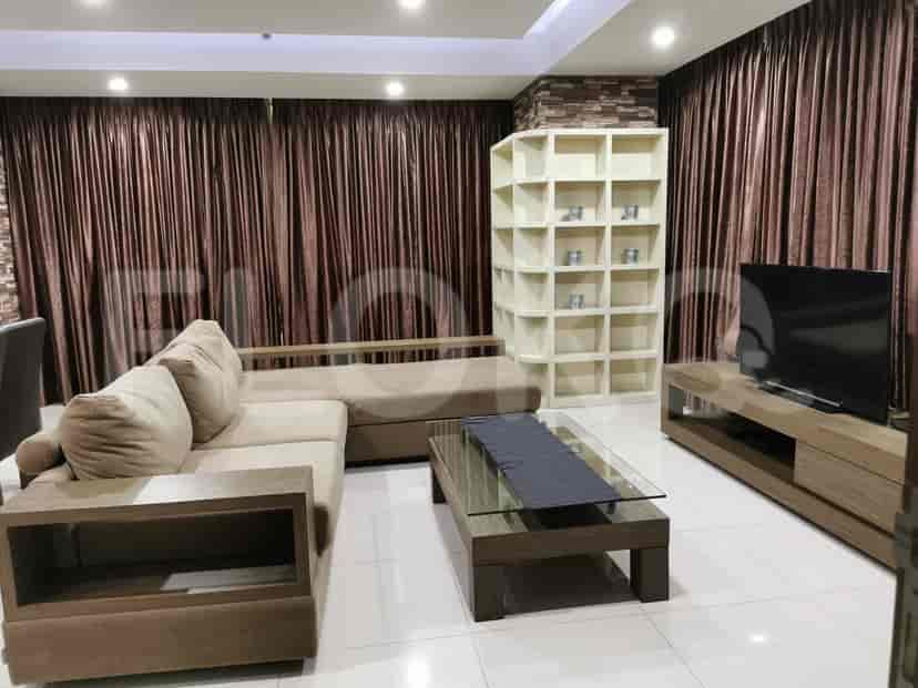 A modern living room with a sectional sofa, glass-top coffee table, and a built-in storage unit.