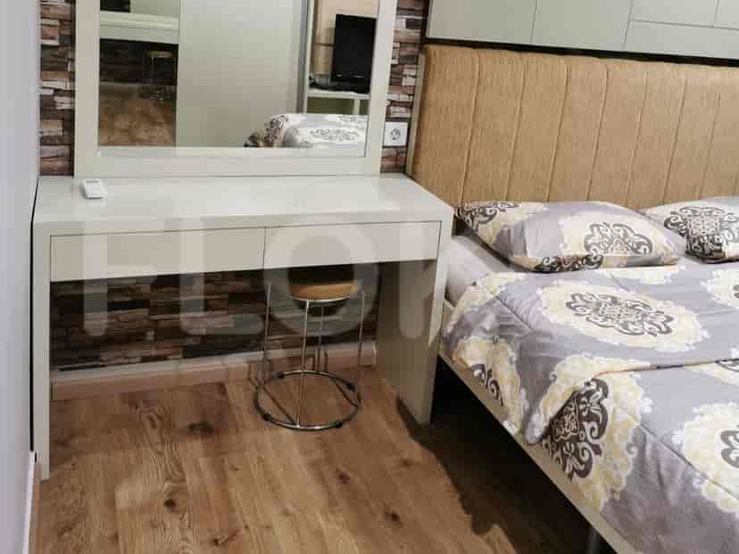 A well-lit bedroom with a double bed, a dresser, and a stool.