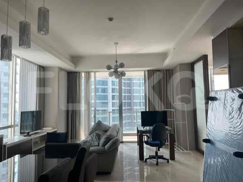 Spacious living room with a sofa, TV, desk area, and large windows.