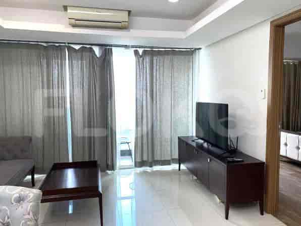 A living room with large windows, a TV, and a coffee table.