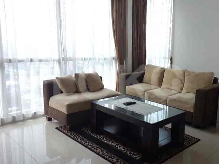 Living room with sofa set and glass table in front of large windows with curtains.