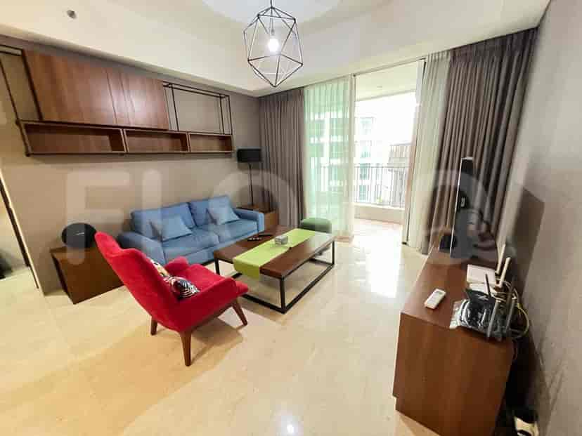 A modern living room with blue sofa, red armchair, and access to a balcony.
