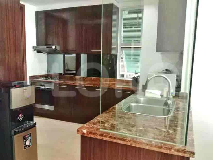 A modern kitchen with wooden cabinets, marble countertops, and stainless steel appliances.