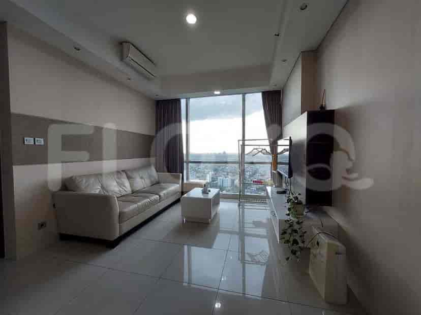 Ruang tamu dengan sofa besar, TV, dan jendela setinggi langit-langit yang menawarkan pemandangan kota.