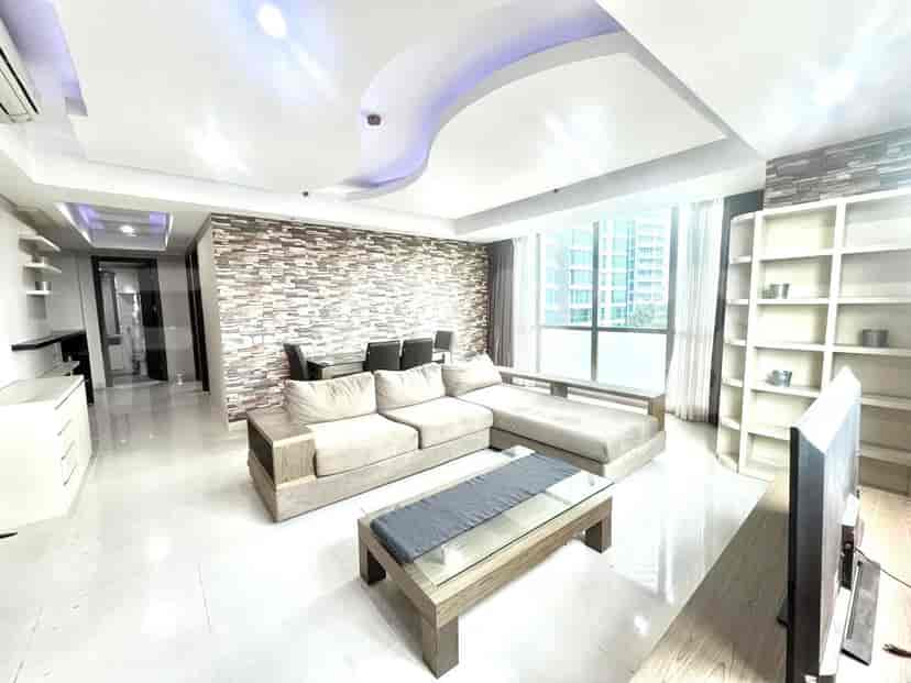 Spacious living room with an L-shaped sofa, TV, and dining area.