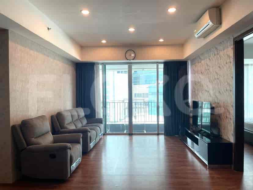 Spacious living room with sofa, TV, and balcony access.