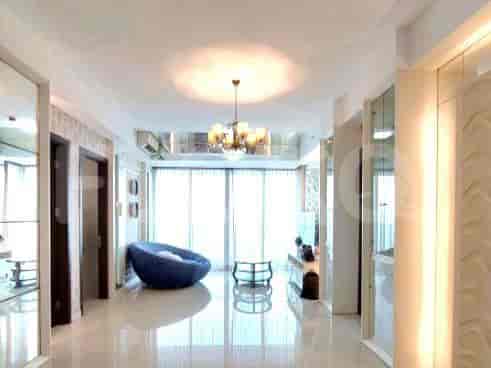 A bright living room with white walls, a chandelier, and large windows.