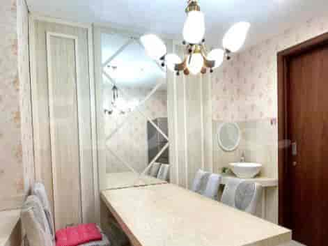 A dining area with a long wooden table, a chandelier, and floral wallpaper.