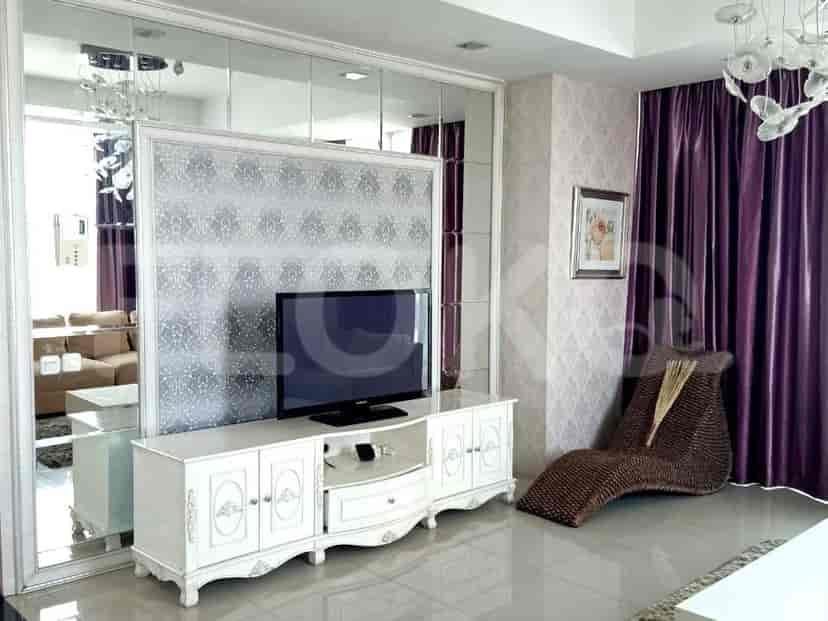 A living room with a TV, decorative chandelier, and a seating area.