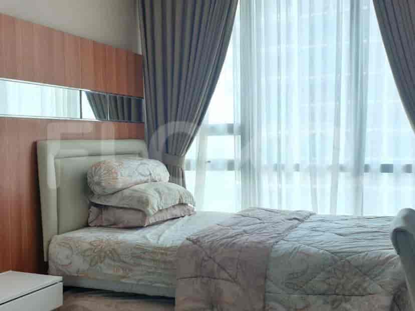 A bedroom with a bed, large windows, and curtains.