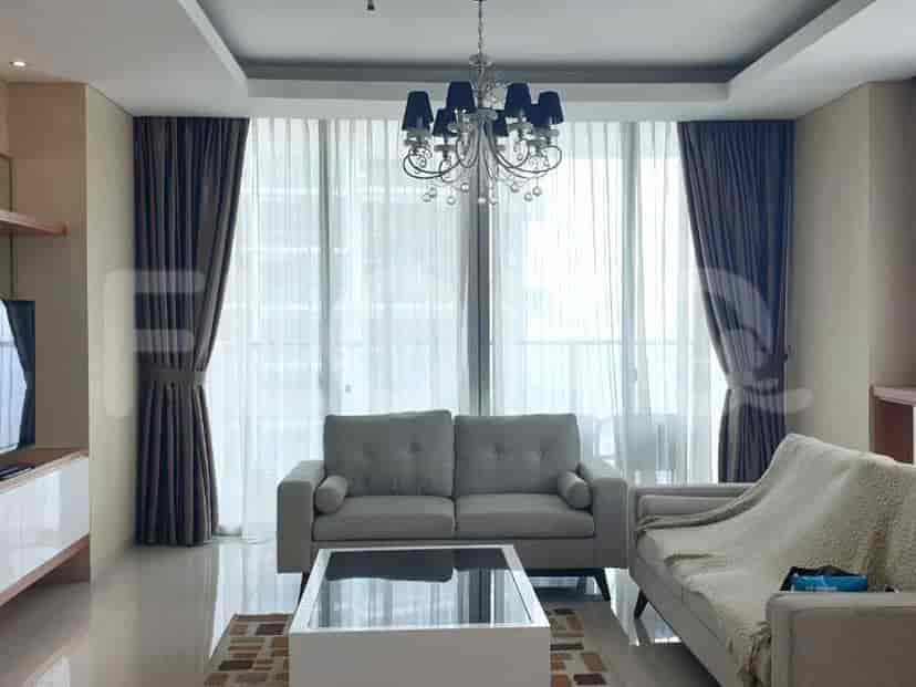 A spacious living room with two sofas, a chandelier, and large windows.