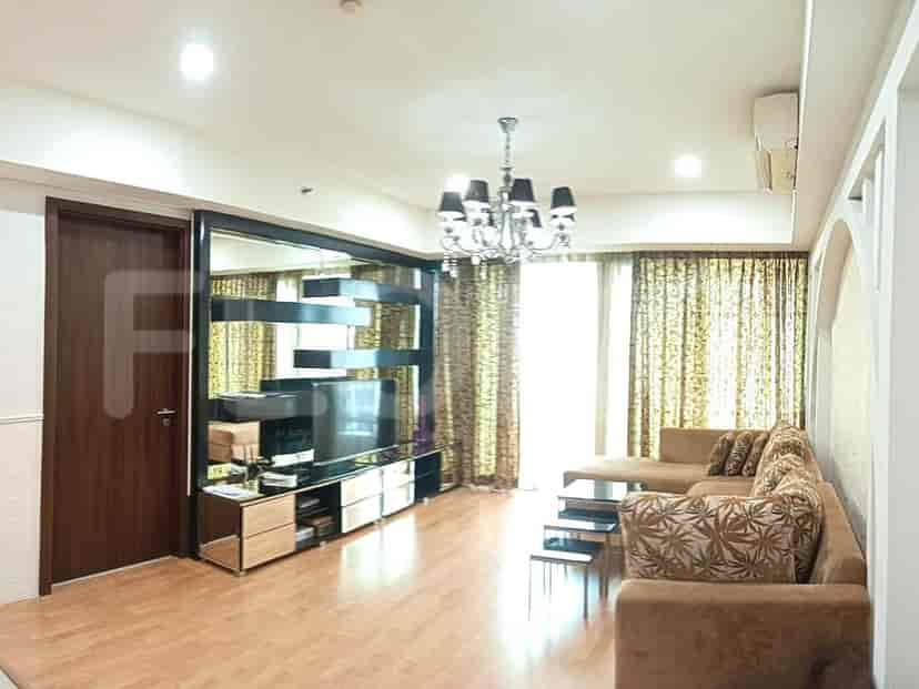 Living room with a TV, brown sofa, and large windows.