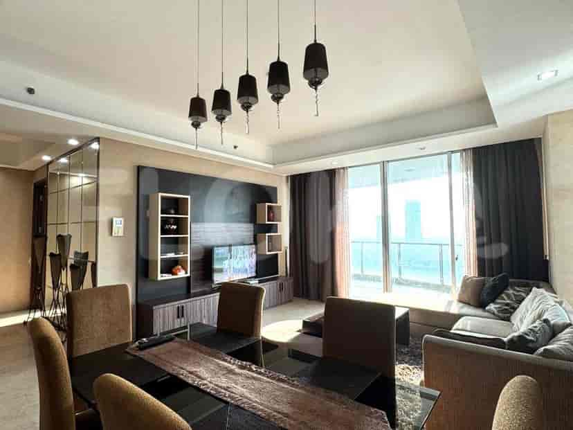 Living room with a smart TV, shelves, and large windows providing a city view.