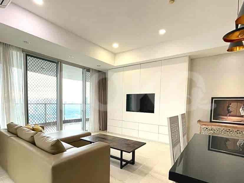 The living room features a TV mounted on white cabinetry, a dining area and access to a balcony.