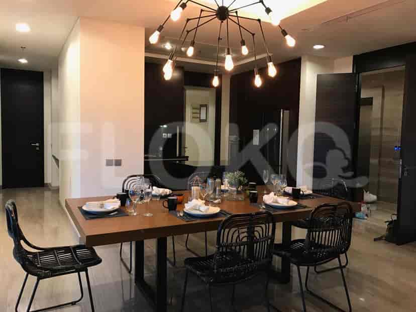 Dining area with a wooden dining table, black chairs, and a modern chandelier.