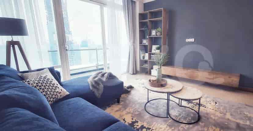 Ruang tamu yang menampilkan sofa biru, rak buku, dan dua meja kopi bundar.