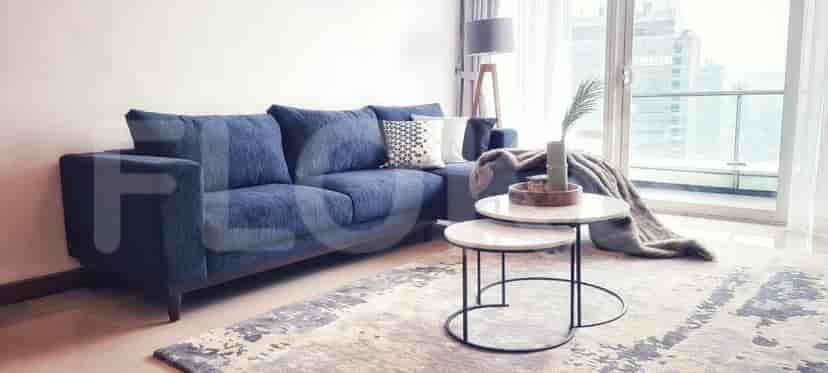 Ruang tamu dengan sofa berbentuk L berwarna biru dan meja kopi.