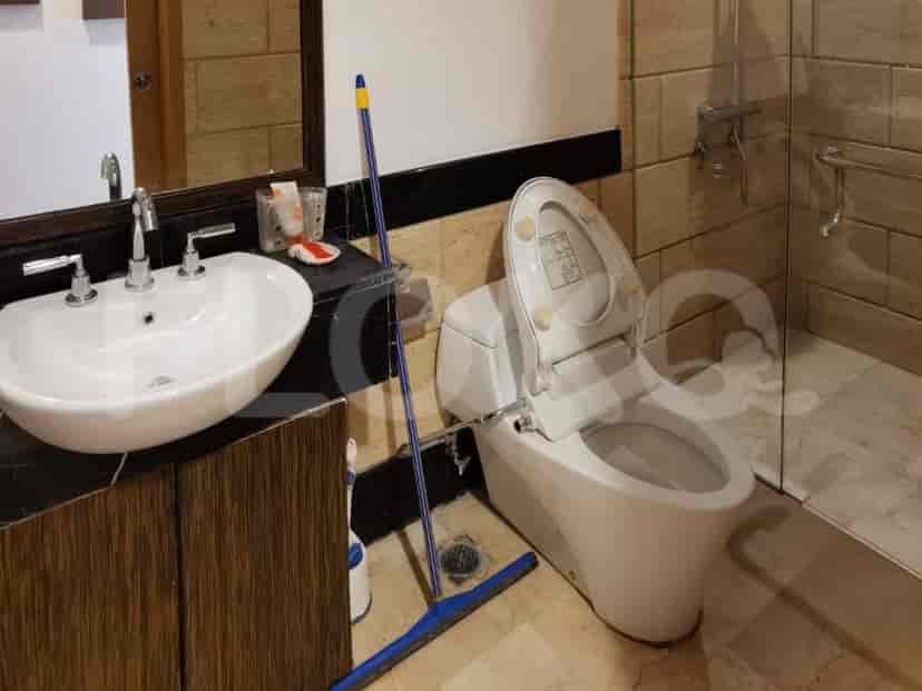 A bathroom with a toilet, sink, and mirror.