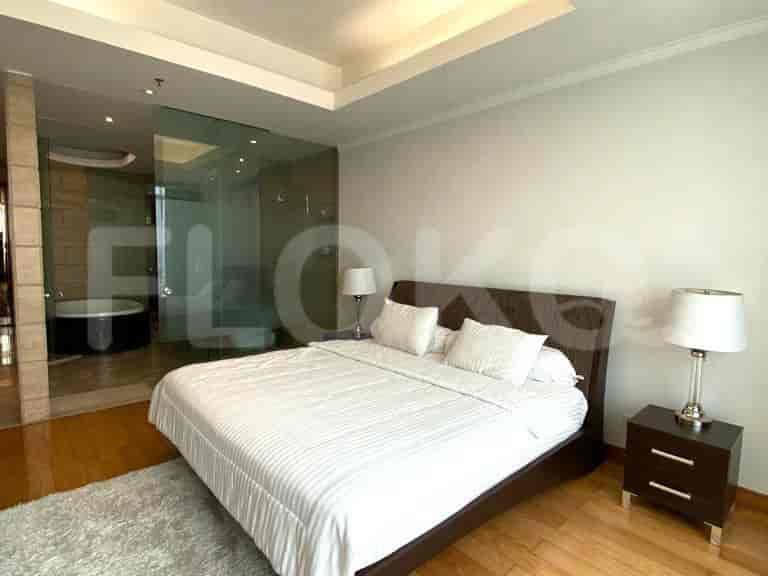 Master bedroom with a large bed and attached bathroom with a glass divider.