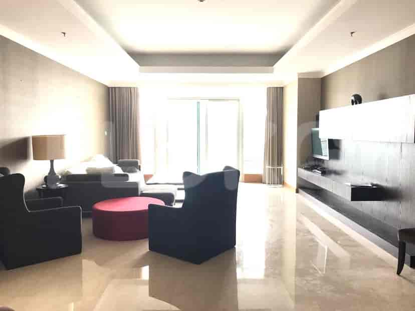 Spacious living room with a grey sofa, red ottoman, and large window.