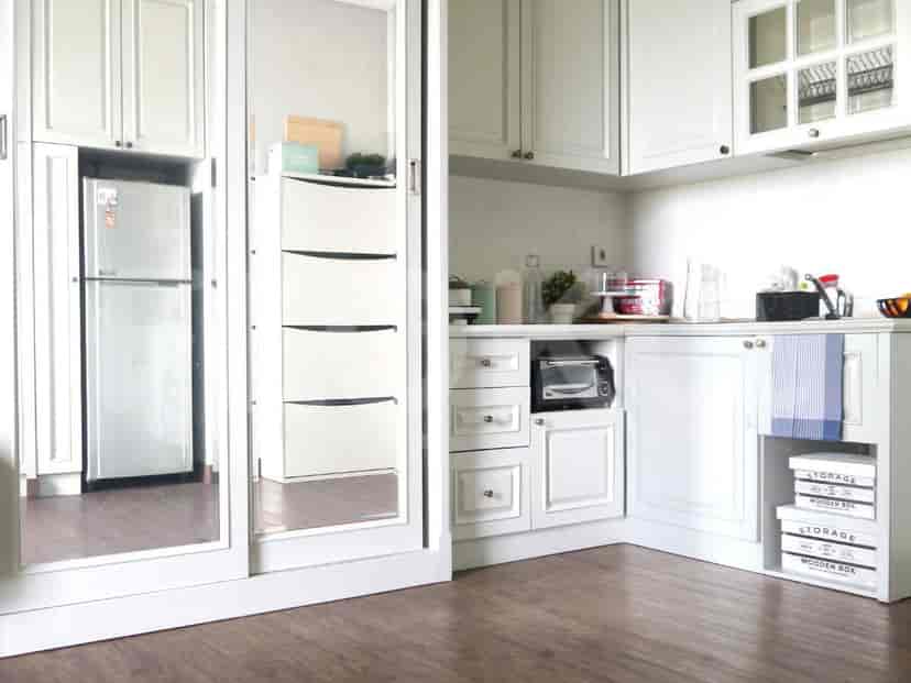 A bright white kitchen with ample storage, incorporating a refrigerator and a built-in microwave.