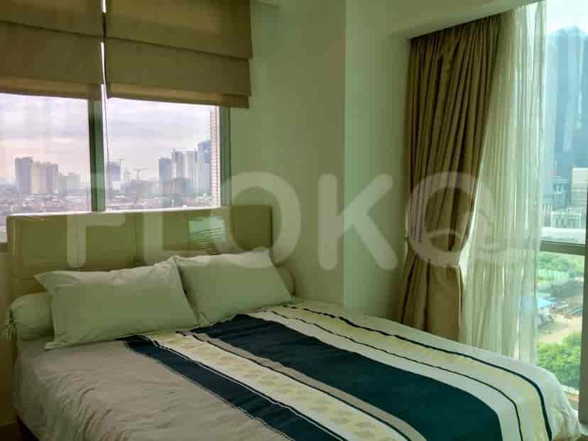 A bedroom with a large bed, neutral color scheme, and large windows.