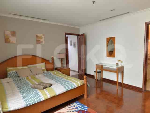 Master bedroom with a large bed, wooden furniture, and artwork.