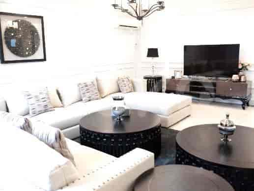 A modern living room featuring a white L-shaped sofa, dark wood coffee tables, and a chandelier.