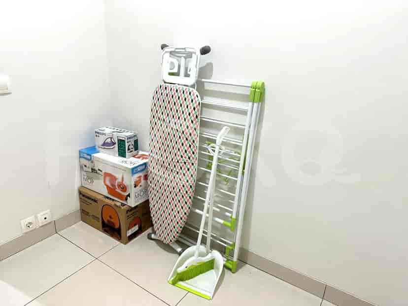 Laundry and storage area with ironing board, drying rack, and cleaning supplies.